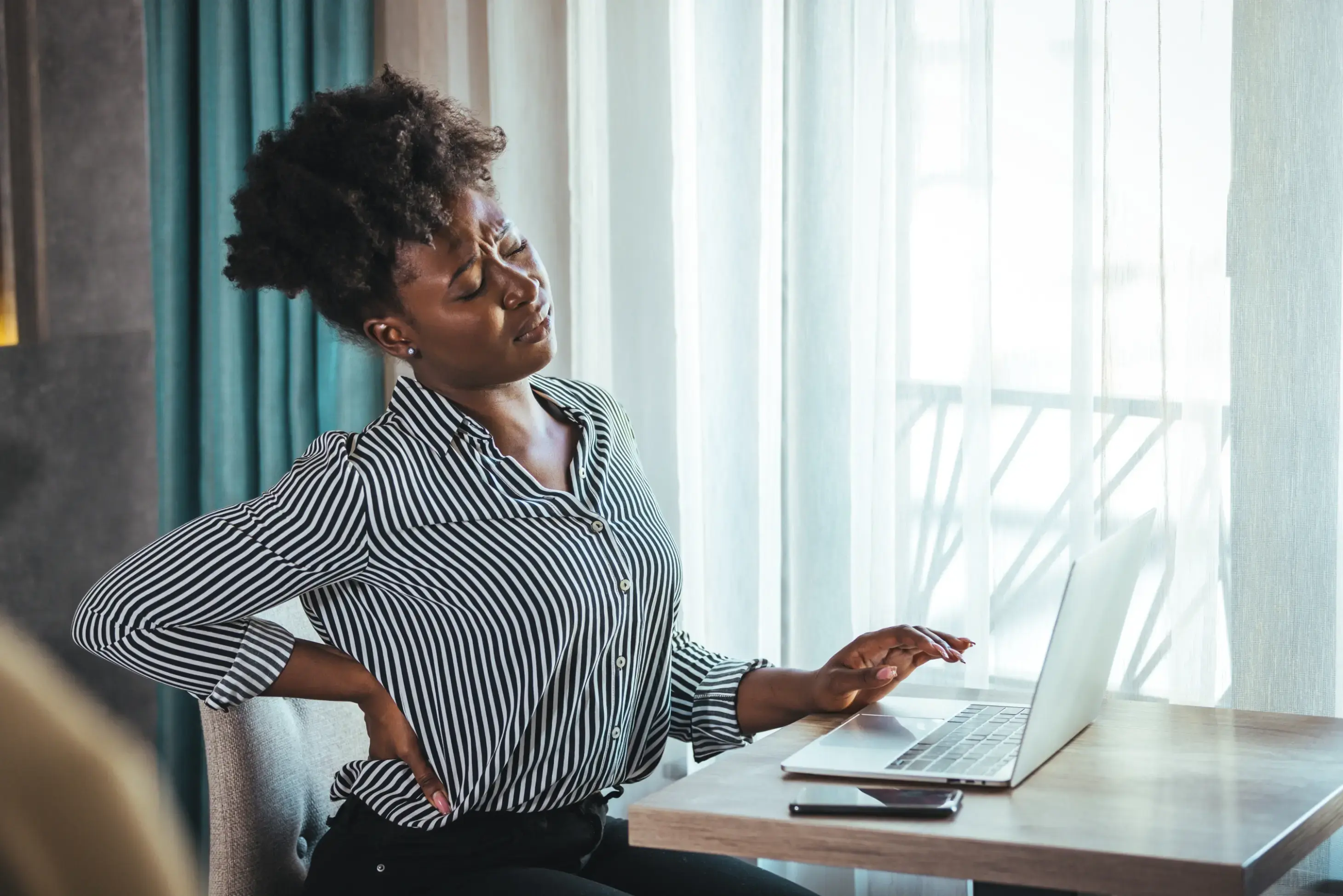 Woman at her desk holding her lower back